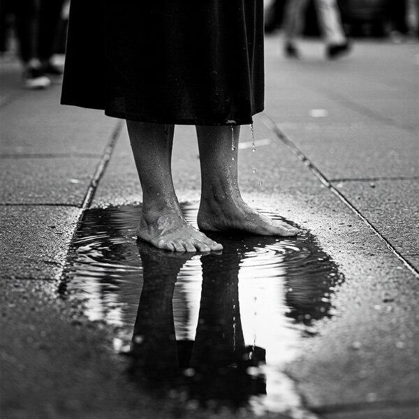 Bare feet stand in a puddle, water dripping from a skirt. A visual echo of climax, collapse, and the holy mess of female humiliation.